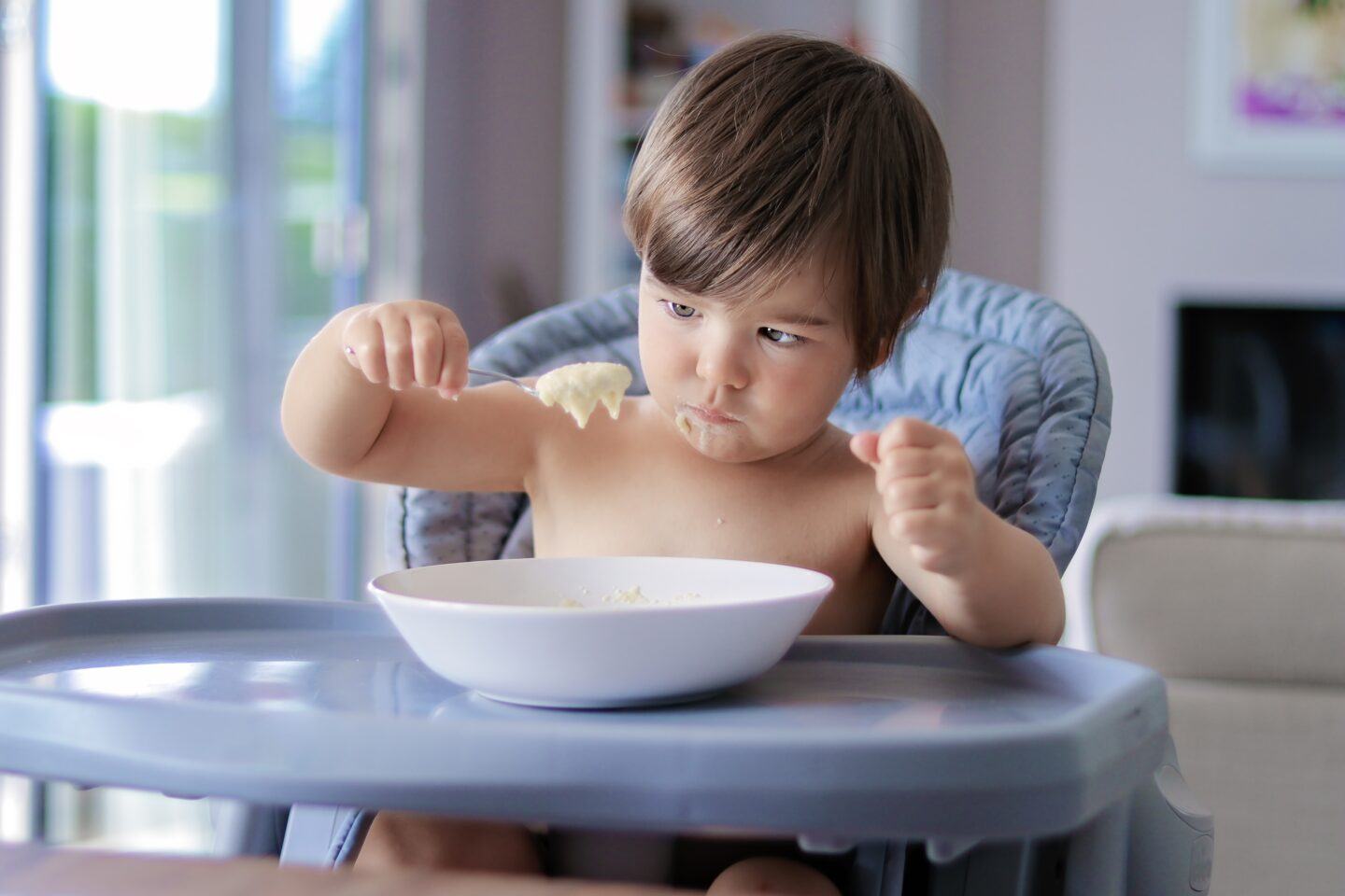 feeding problems: baby looking at food on spoon in high chair