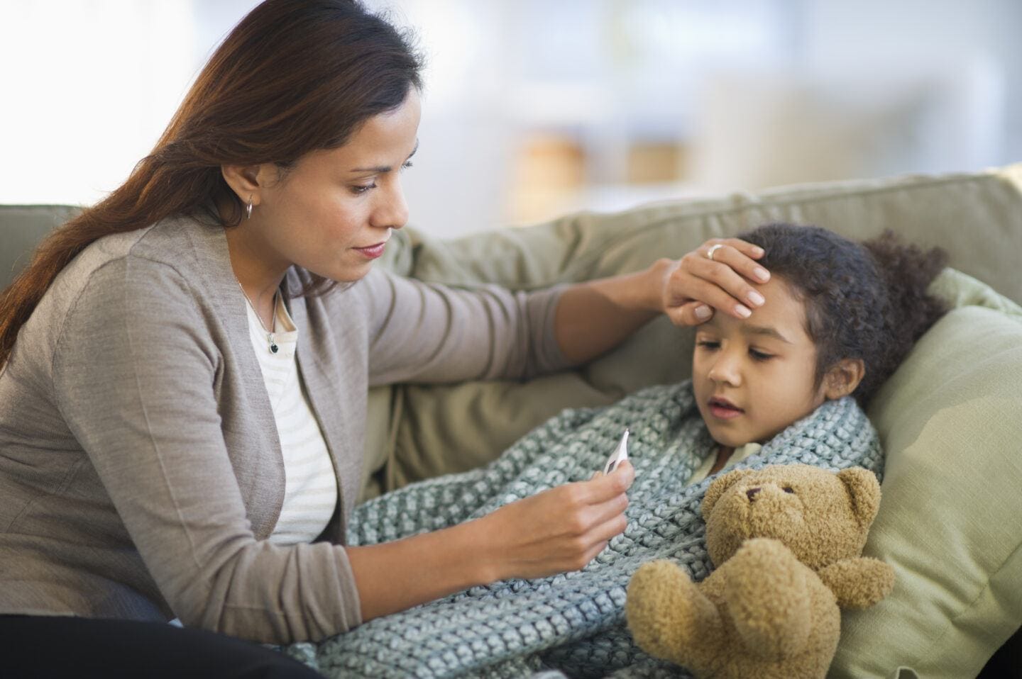 bovine colostrum: mother takes temperature of sick child on couch