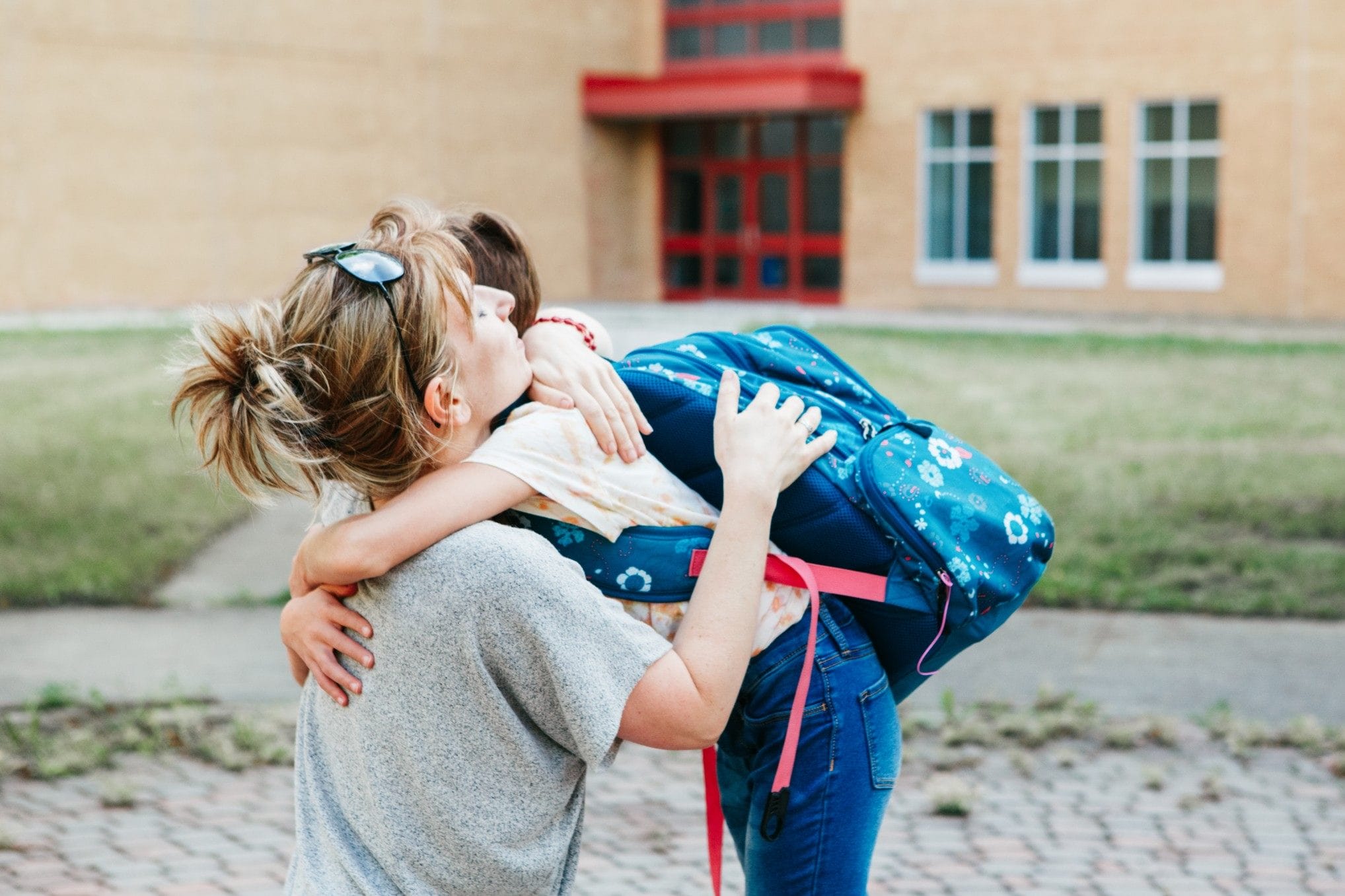 mom hugging son wearing a backpack