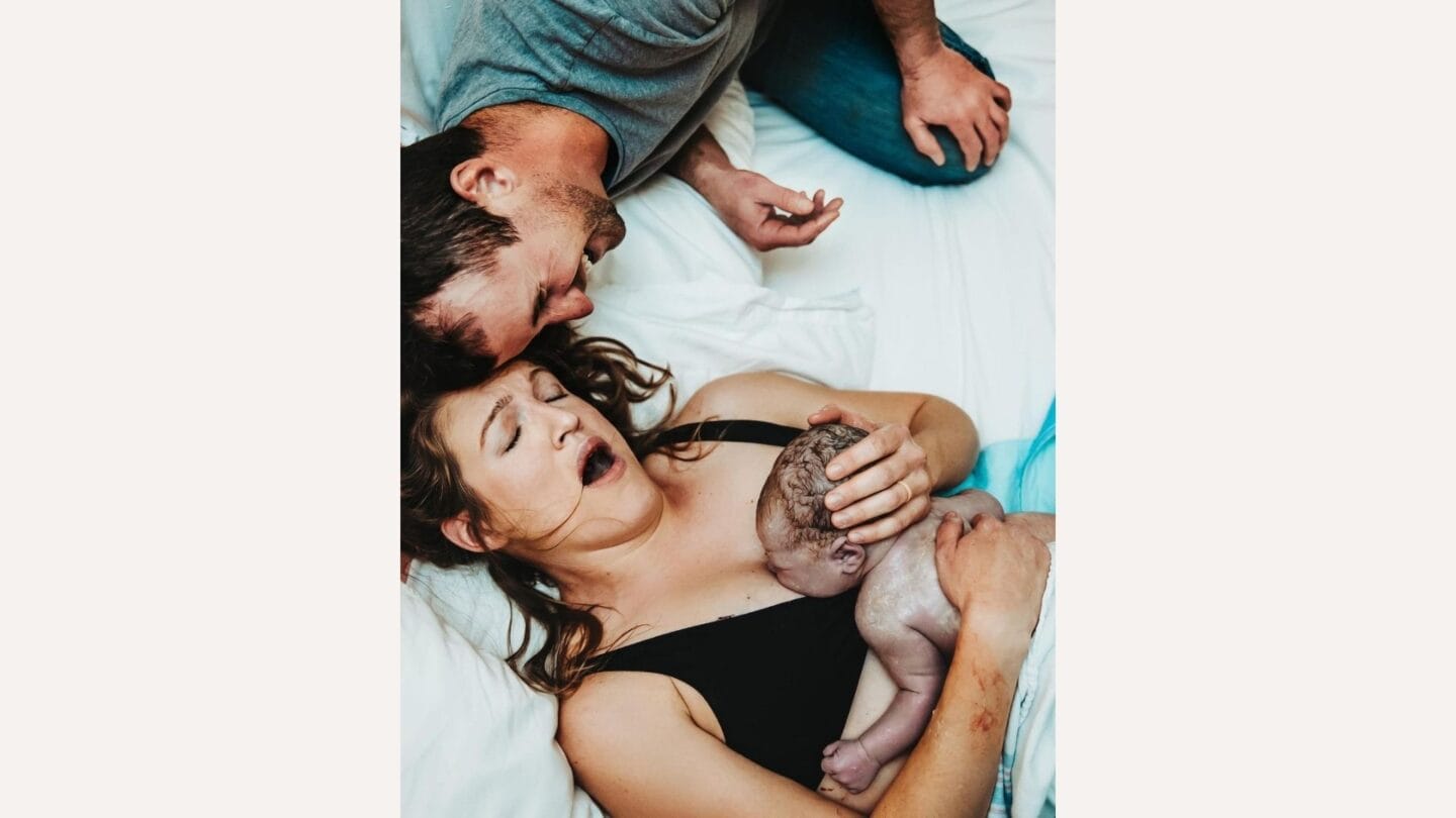 photo of father with mother holding baby after giving birth