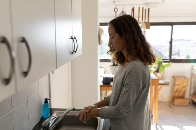 woman washing hands at home in kitchen