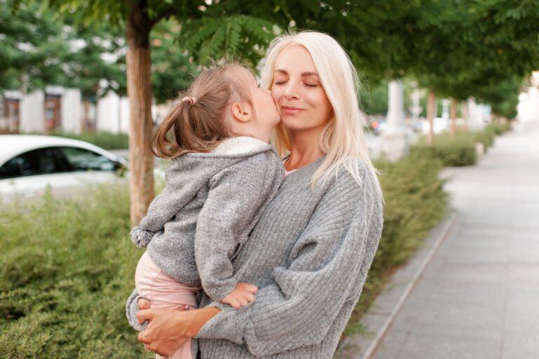 sharing saliva: toddler kisses mom on cheek outside