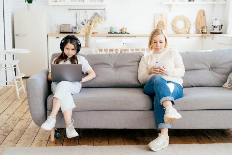 parenting style: mom and daughter on phone and computer sitting on couch