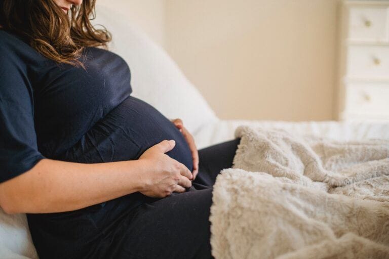 tokophobia: pregnant woman holding baby bump at home in bed