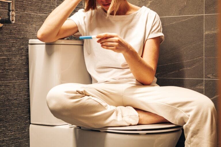 get pregnant on your period: woman waiting for pregnancy test in bathroom