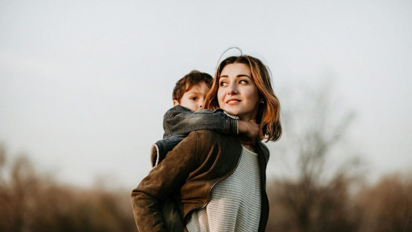 son on mama's back in field