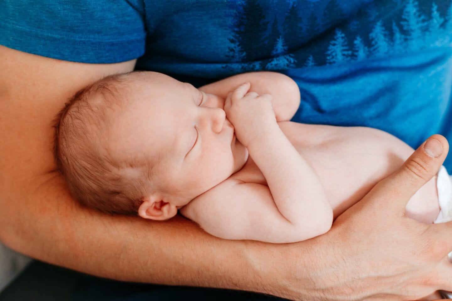 father holding newborn baby in arms