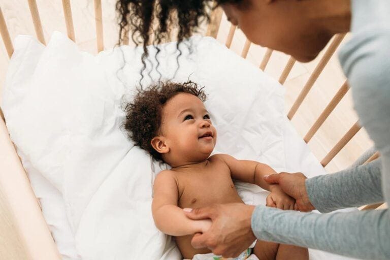 mom looking at baby in the crib