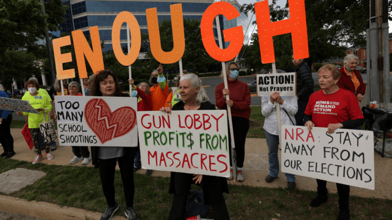 Uvalde school shooting vigil participants holding anti-gun signs.