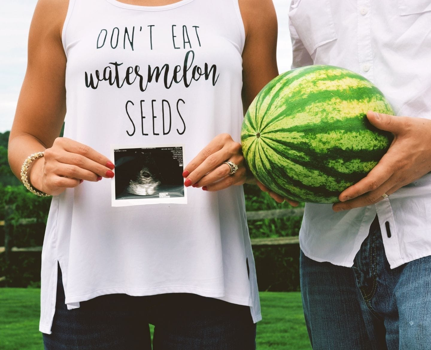 woman holding ultrasound and man holding watermelon for a pregnancy announcement