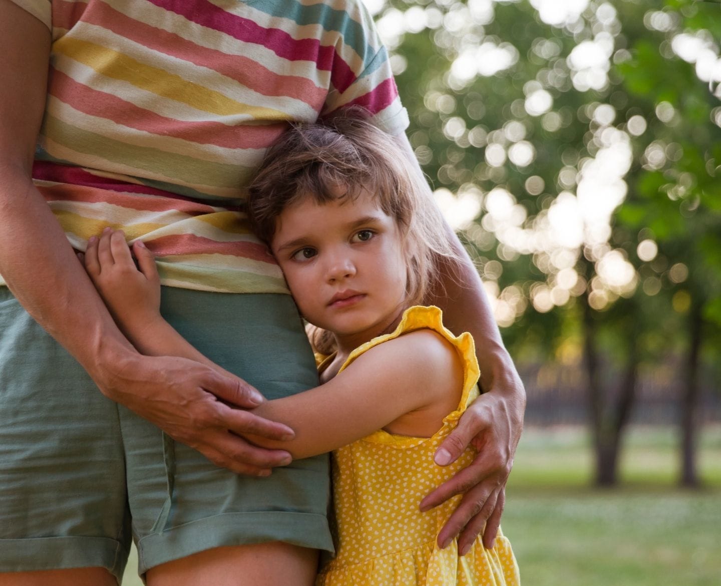 little girl crying with arms wrapped around mother's waist