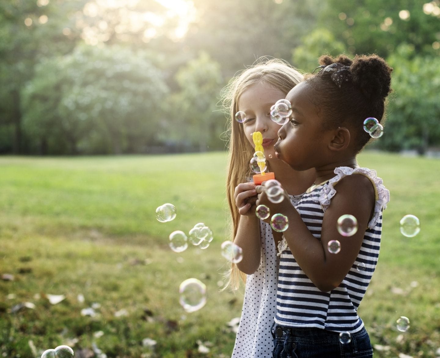 magic of summer: two little girls blowing bubbles