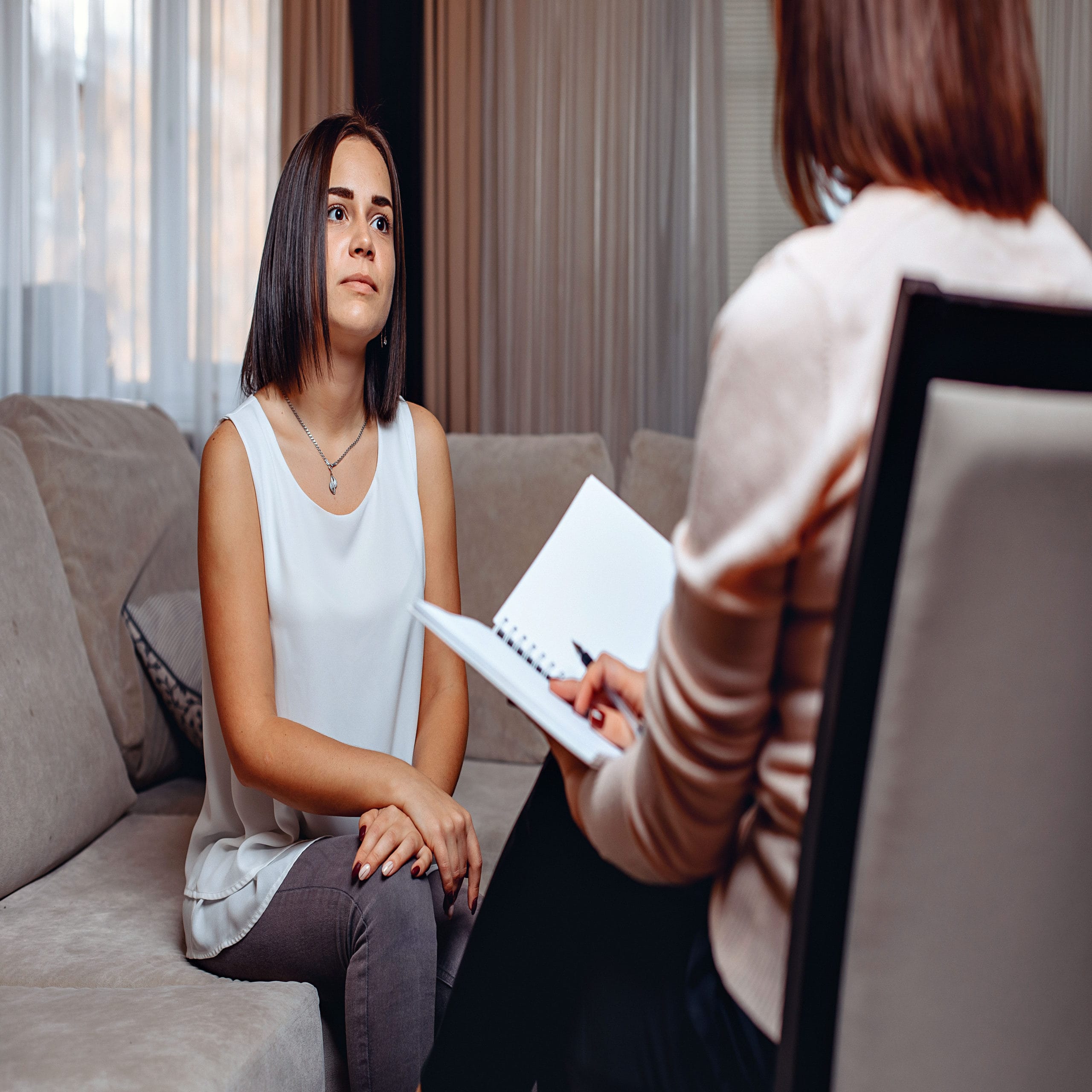 postpartum depression maternal mental health woman sits on couch in doctor's office