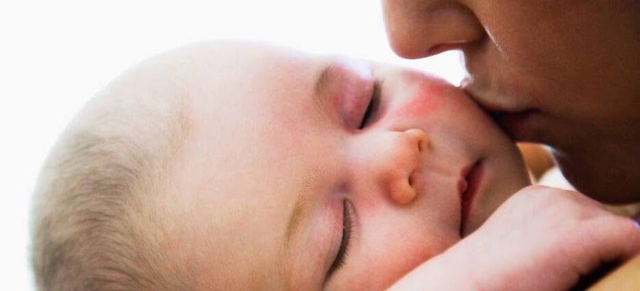 mom kissing baby on the cheek