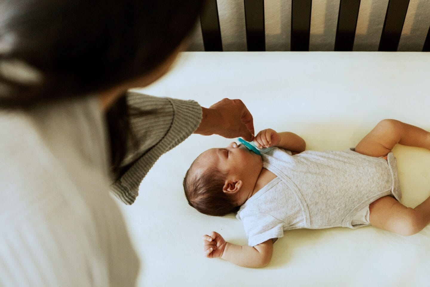 baby sleeping in crib mom offering pacifier