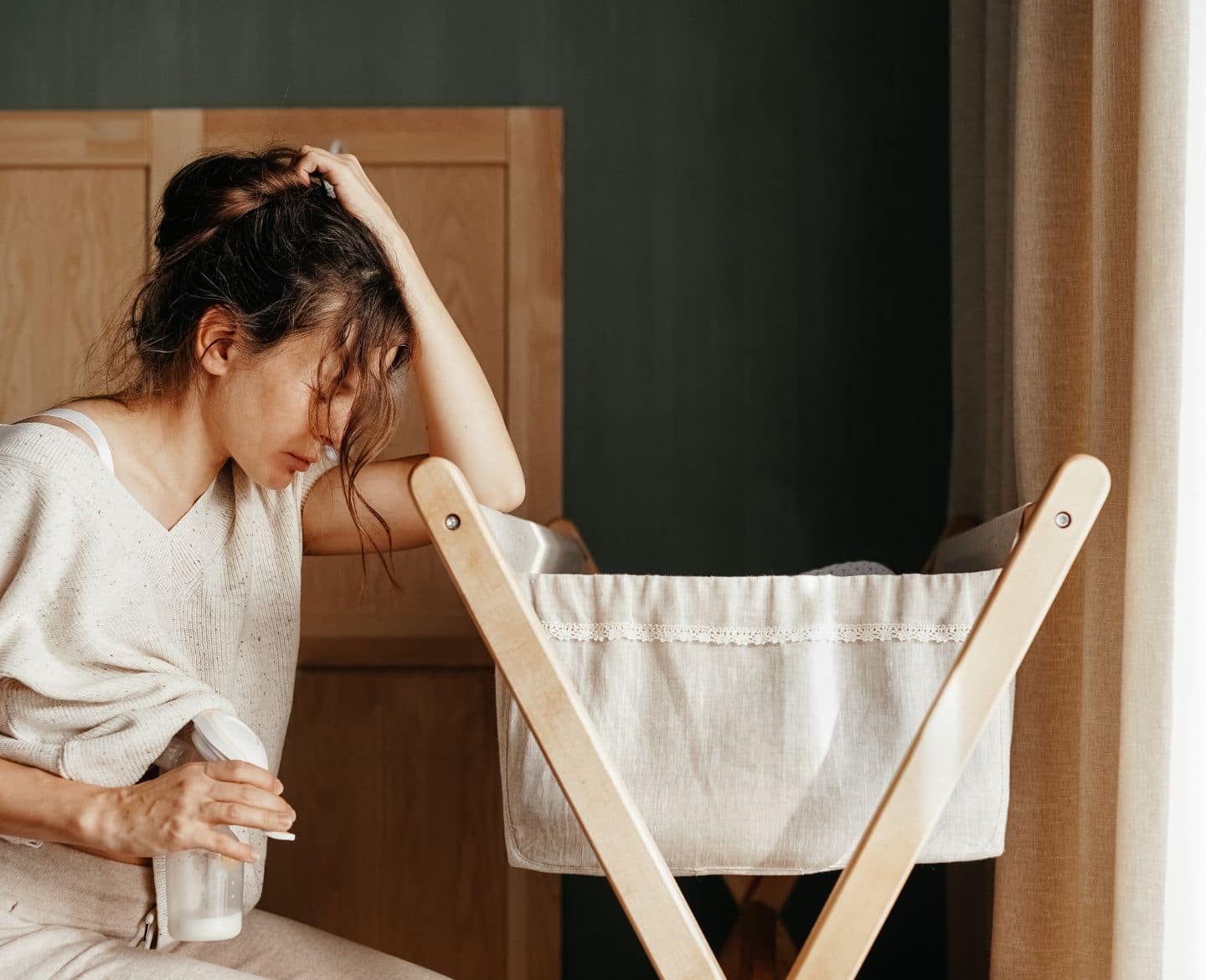 tired mom holding head and pumping