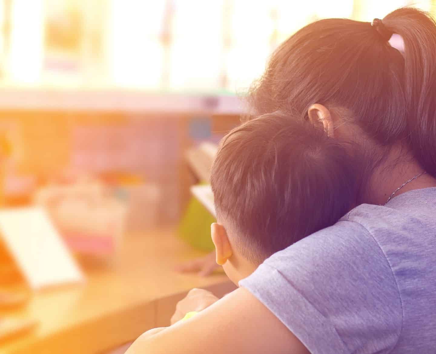 Mother comforting young son at home