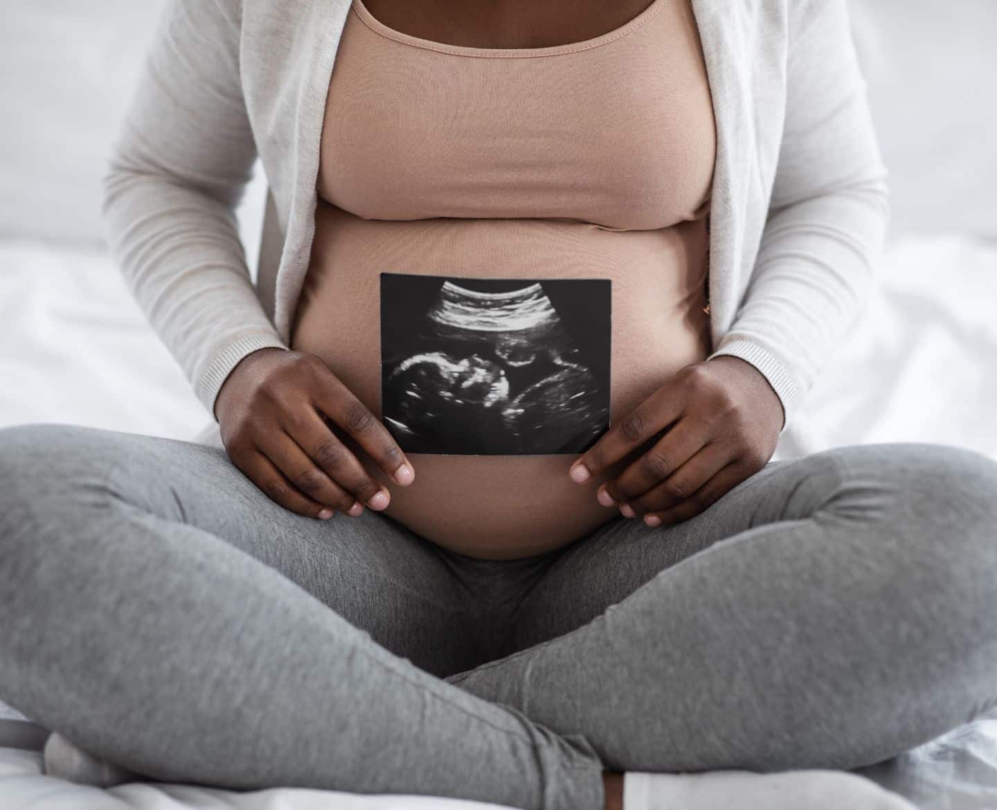 Pregnant woman holding sonogram in front of belly