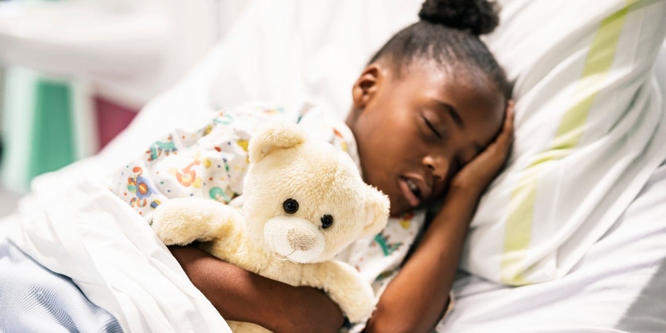 young girl sleeping in bed with teddy bear - sleep for kindergarten success