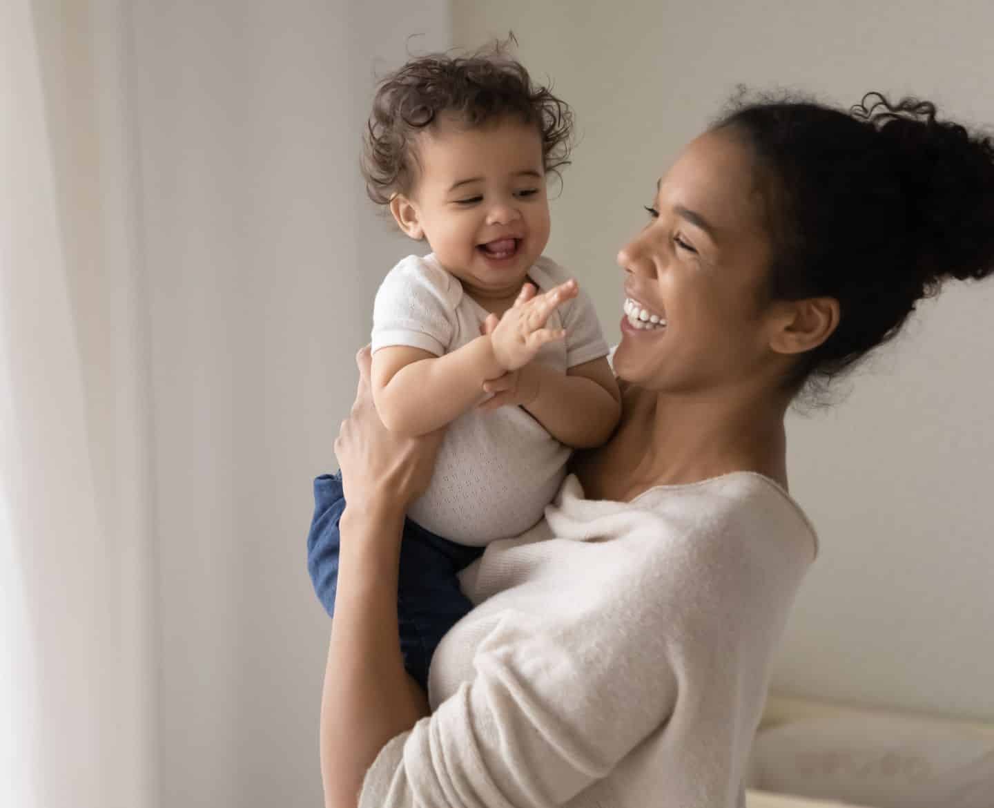 mom smiling while holding toddler