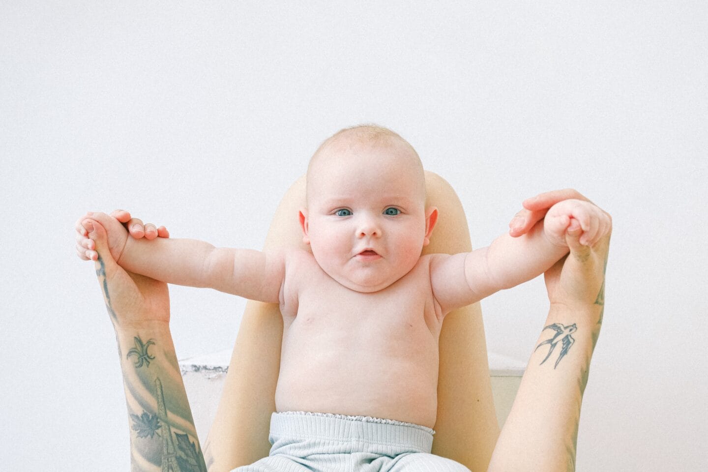 tattood mom holding baby's hands