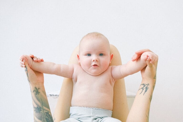 tattood mom holding baby's hands