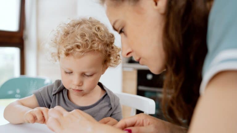 default parent mom sitting at table helping son with an activity