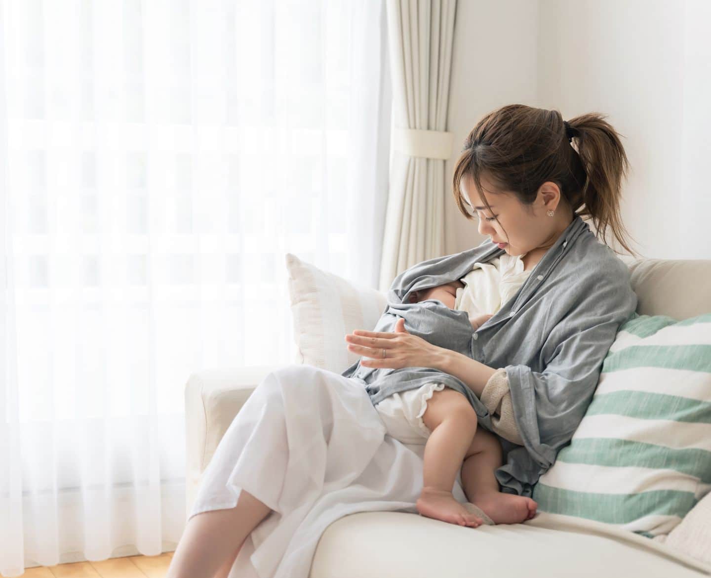 mom breastfeeding child sitting on the couch