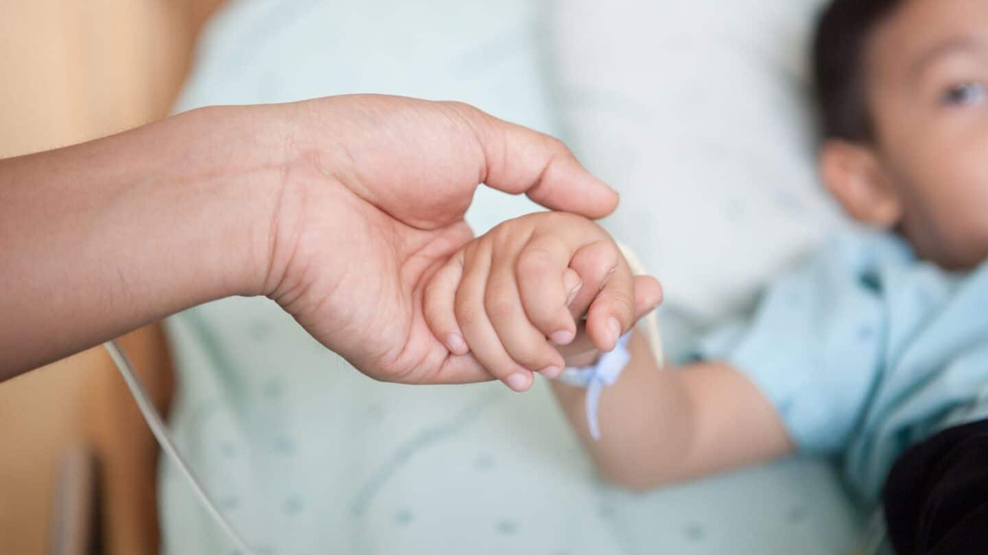 mom holding baby's hand in hospital - Motherly's partnership with the Dare to Dream Project