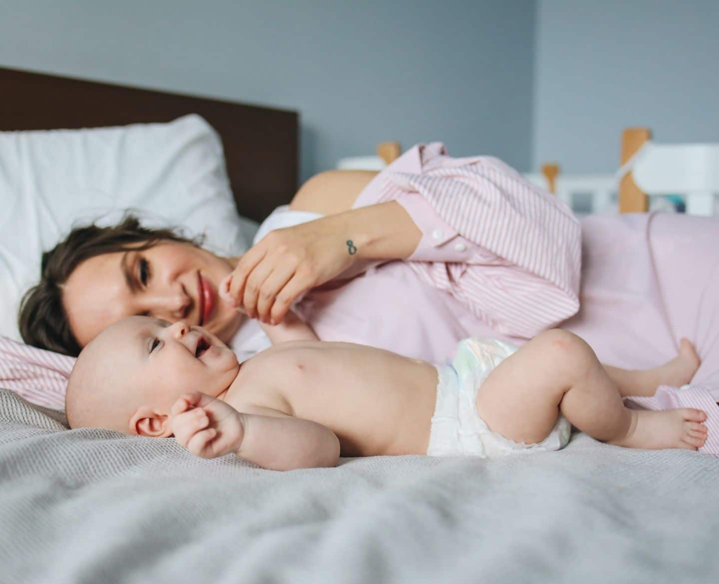 smiling mom and baby lying on bed - quality time