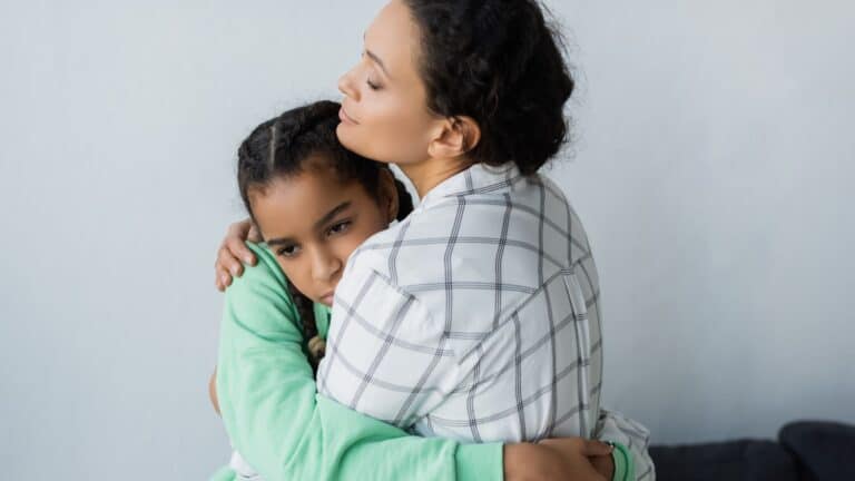 upset preteen daughter hugging mom who feels like mean mom