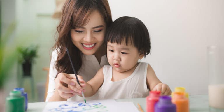 mom teaching her baby to paint, celebrating the mom milestone of patience