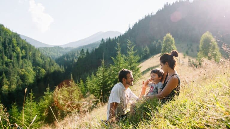 mother father kid sitting on hill- unique vacation rentals