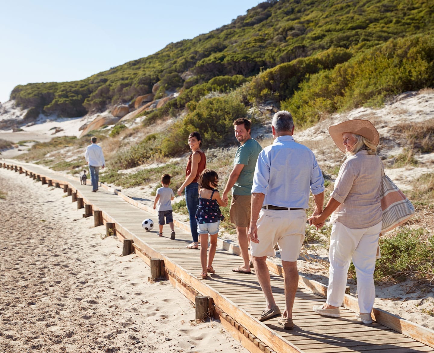 on a family vacation with grandparents, a multigenerational family walking on the beach