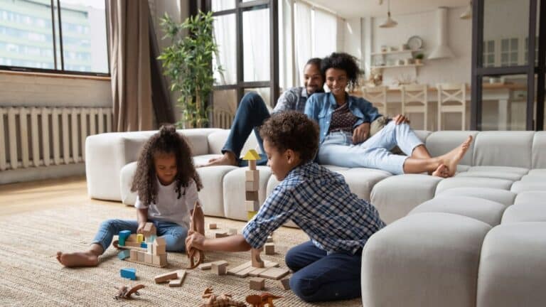 sittervising parents sitting on couch watching son and daughter play with blocks