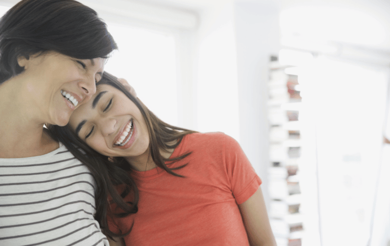 teen daughter leaning her head on mom and laughing