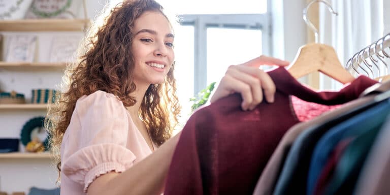 Woman looking through rack of old clothes to recycle