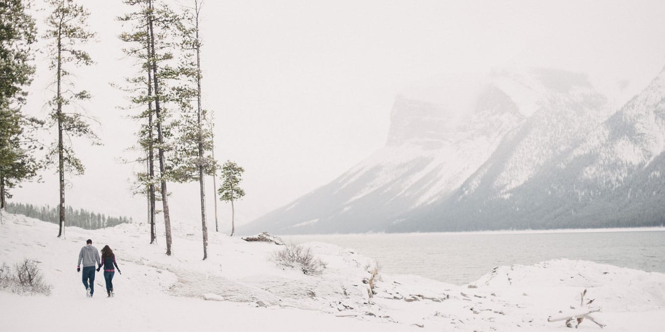 couple walking through the snow in the mountains -bucket list trips