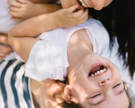 mom tickling her son outdoors Motherly