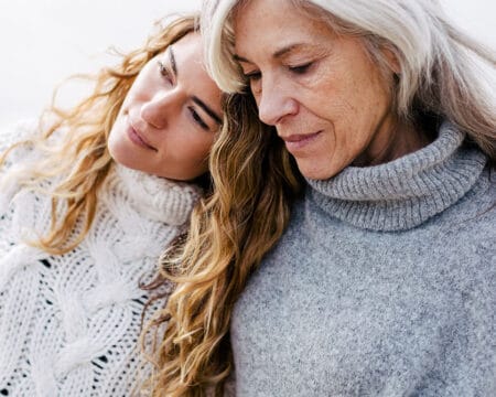 senior mom and daughter hugging outdoors Motherly