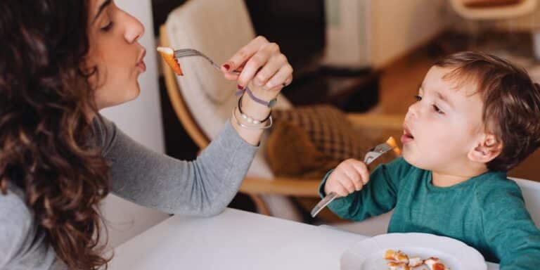 mom eats dinosaur nuggest with kids as she read tips for feeding kids