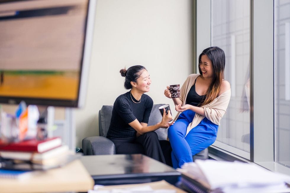 two women drinking tea and laughing Motherly