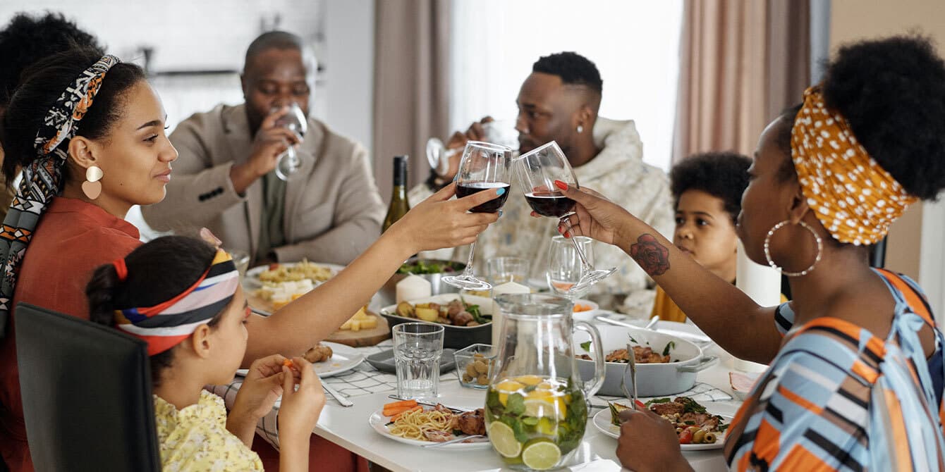 women cheersing at thanksgiving dinner - how to host thanksgiving on a budget