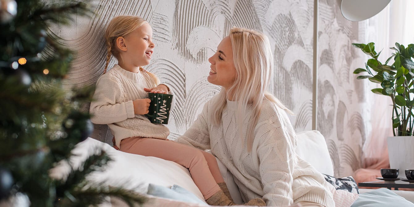 mom and daughter laughing on the couch on christmas - co parenting during the holidays