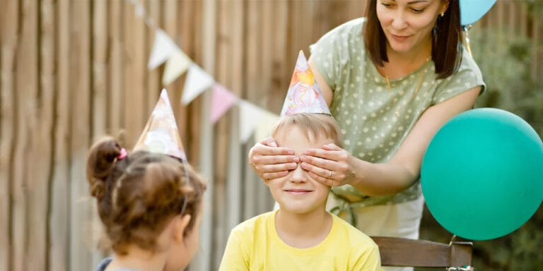 mom covering sons eyes for surprise childhood birthday parties