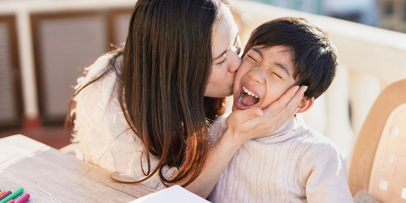 mom kissing son on cheek- optimistic child