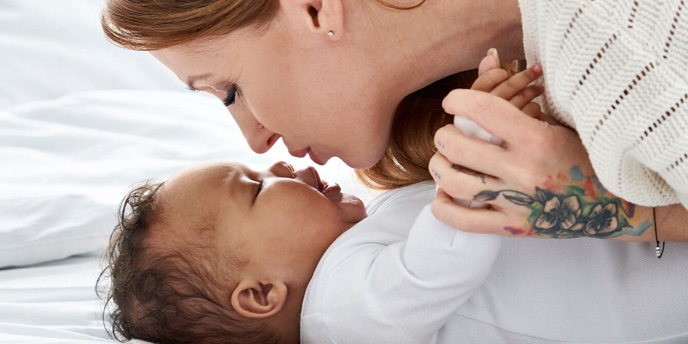 mom leaning over her baby, learning how to teach baby to talk