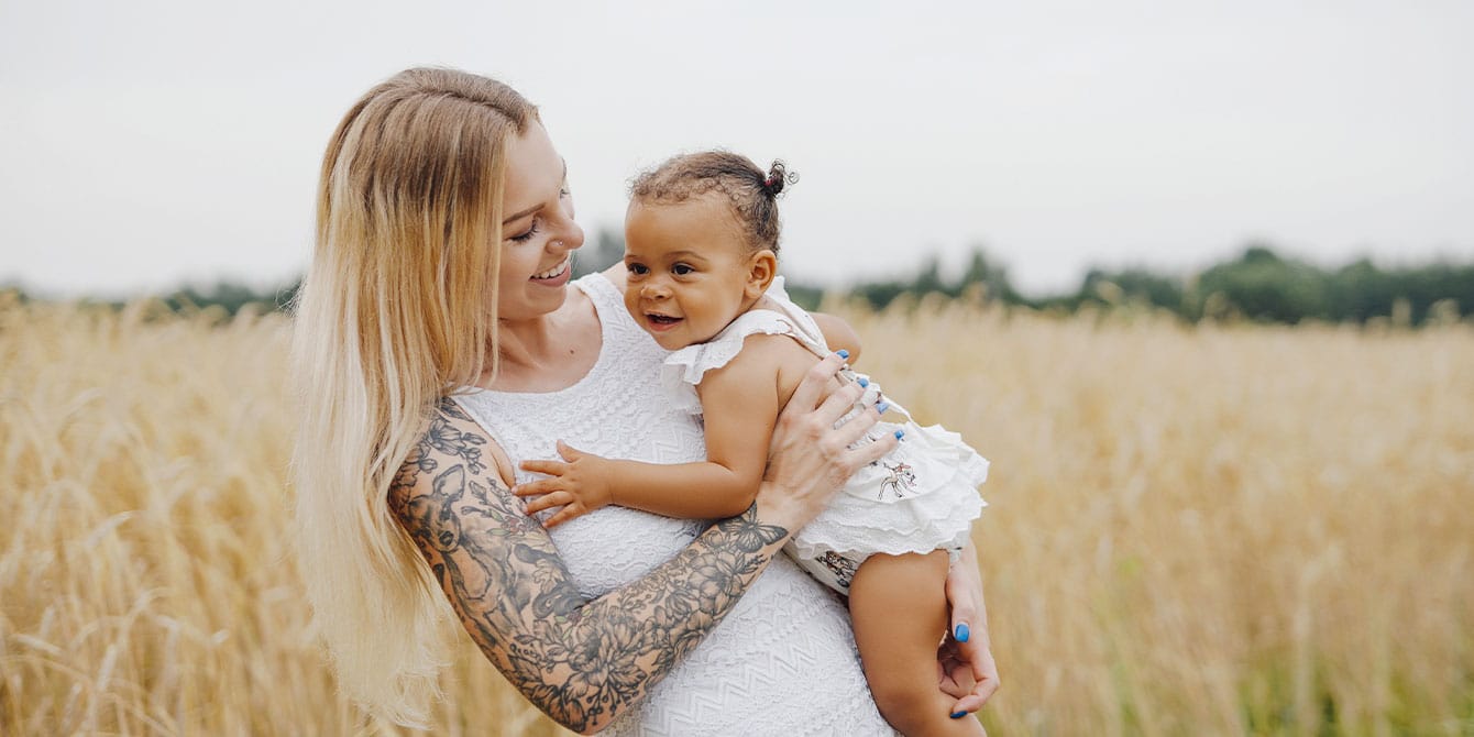 mom with tattoos in an open field with child- birth flower tattoos