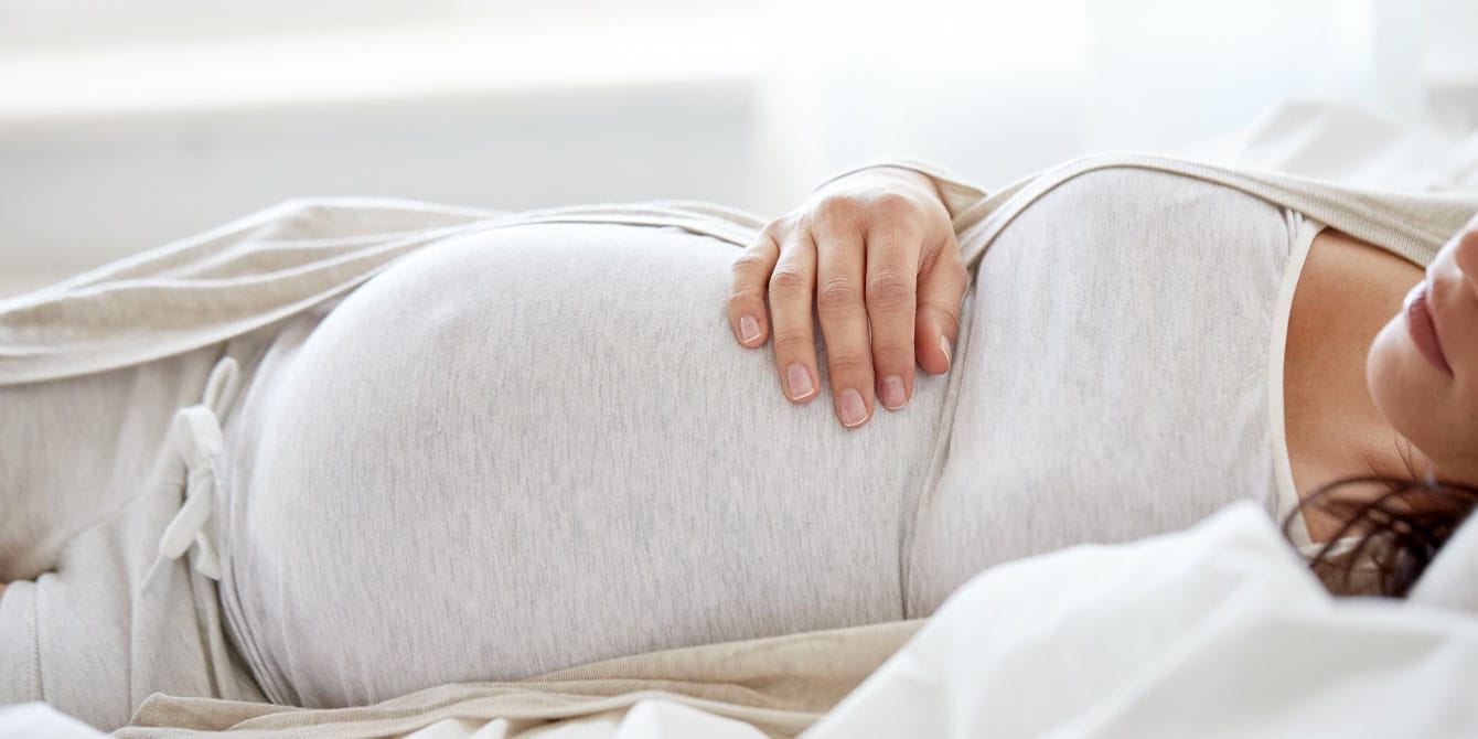 pregnant woman laying down holding her stomach medical interventions for pregnancy