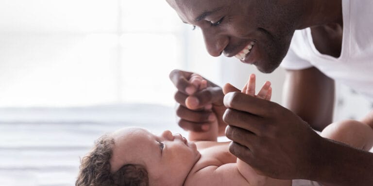 smiling father playing with his baby normalize paternity leave